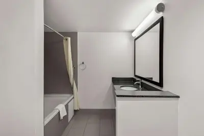 a bathroom with a sink and a mirror and a tub at Best Western Luxbury Inn Fort Wayne in Fort Wayne
