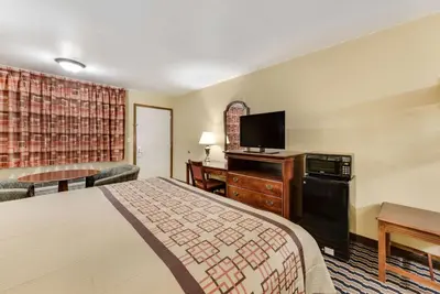 a hotel room with a bed and a flat screen tv at Rodeway Inn Columbus West in Columbus