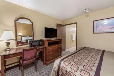 a hotel room with a bed and a desk and a mirror at Rodeway Inn Columbus West in Columbus
