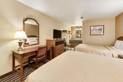 a hotel room with two beds and a desk and a mirror at Rodeway Inn Columbus West in Columbus