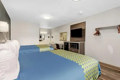 a hotel room with two beds and a flat screen tv at Grove City Travel Inn South Columbus in Grove City
