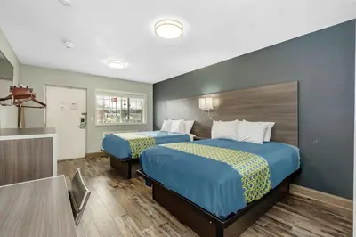 a hotel room with two beds and a table at Grove City Travel Inn South Columbus in Grove City