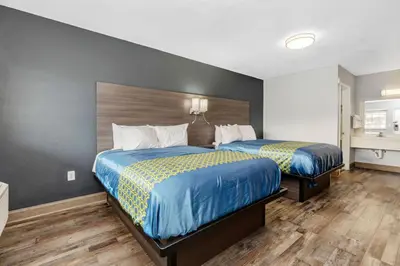 a bedroom with two beds with blue and yellow sheets at Grove City Travel Inn South Columbus in Grove City