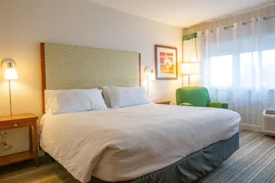 a bedroom with a large bed and a green chair at Holiday Inn Express Columbus Airport Easton in Columbus