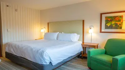 a hotel room with a bed and a green chair at Holiday Inn Express Columbus Airport Easton in Columbus