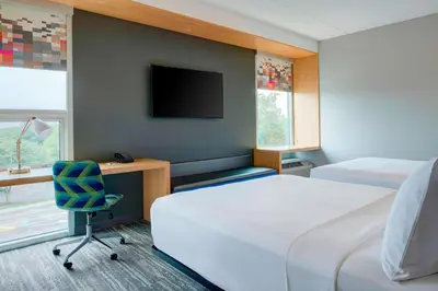 a hotel room with two beds and a desk and a tv at Aloft Columbus Westerville in Westerville