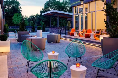 a patio with green chairs and tables in front of a building at Aloft Columbus Westerville in Westerville