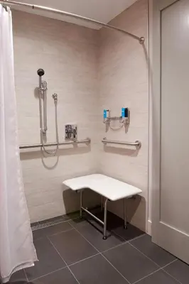 a shower stall with a bench in a bathroom at Aloft Columbus Westerville in Westerville