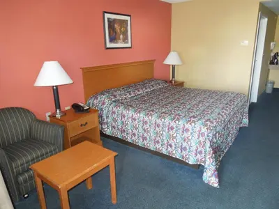 a hotel room with a bed and a chair at Kozy Inn Columbus in Columbus
