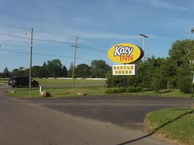 a kiwi inn sign next to a road at Kozy Inn Columbus in Columbus