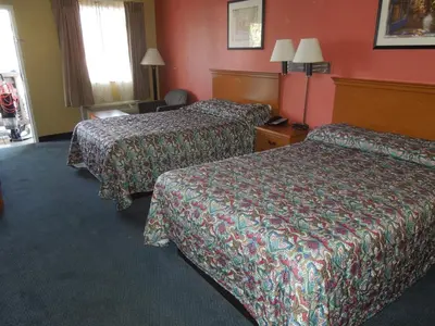 two beds in a hotel room with red walls at Kozy Inn Columbus in Columbus