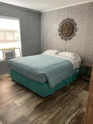 a bedroom with a bed with a blue comforter at Lake Point Motel in Marblehead