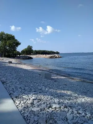 a beach with rocks and the water and trees at Lake Point Motel in Marblehead
