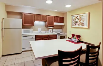 a kitchen with a white table and a white refrigerator at Hawthorn Extended Stay by Wyndham Columbus in Columbus