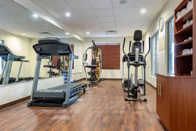 a gym with several tread machines in a room at Holiday Inn Express & Suites Hebron - Cincinnati Airport by IHG in Hebron