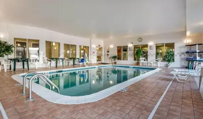 a large swimming pool in a hotel with tables and chairs at Holiday Inn Express & Suites Hebron - Cincinnati Airport by IHG in Hebron