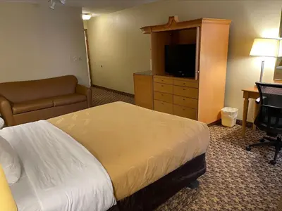a hotel room with a bed and a desk and a television at Baymont by Wyndham Greenfield in Greenfield