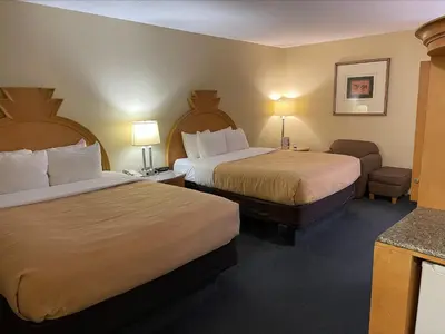 a hotel room with two beds and a chair and a table at Baymont by Wyndham Greenfield in Greenfield