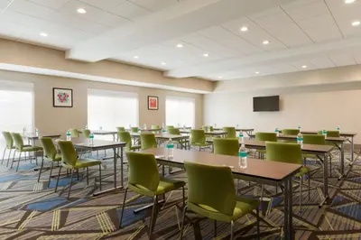 a conference room with tables and chairs and a screen at Holiday Inn Express & Suites - Cincinnati NE - Red Bank Road by IHG in Cincinnati