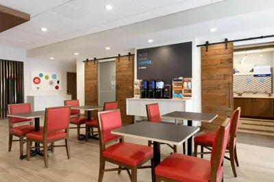 a dining room with tables and red chairs at Holiday Inn Express & Suites - Cincinnati NE - Red Bank Road by IHG in Cincinnati
