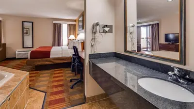 a hotel room with a bathroom with a sink and a bed at Best Western Lakewood Inn in Hebron