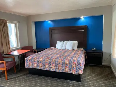 a hotel room with a bed and a blue wall at Best Motel in Johnston Corners