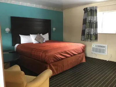 a hotel room with a bed and a chair at Best Motel in Johnston Corners