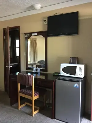 a room with a desk with a microwave and a microwave at Best Motel in Johnston Corners