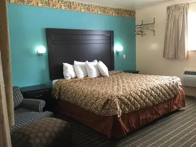 a hotel room with a bed and a chair at Best Motel in Johnston Corners