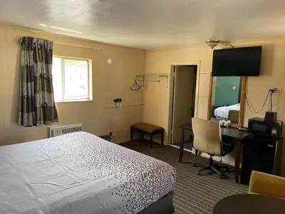 a hotel room with a bed and a desk and a bedroom at Best Motel in Johnston Corners