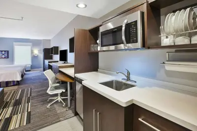 a kitchen with a sink and a room with a bed at Home2 Suites By Hilton Pittsburgh Area Beaver Valley in Monaca