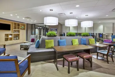 a waiting room with a couch and tables and chairs at Home2 Suites By Hilton Pittsburgh Area Beaver Valley in Monaca