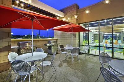 a patio with tables and chairs and umbrellas at Home2 Suites By Hilton Pittsburgh Area Beaver Valley in Monaca