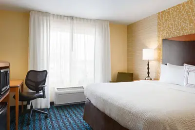 a hotel room with a bed and a chair and a window at Fairfield Inn & Suites by Marriott Weirton in Weirton