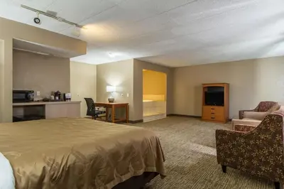 a hotel room with a bed and a living room at GreenRidge Hotel in Wickliffe