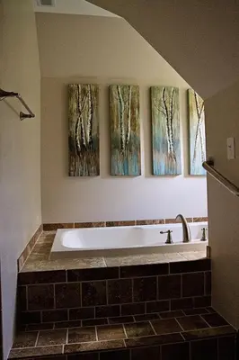 a bath tub in a bathroom with three paintings on the wall at Wishmaker House B&b in Bellville
