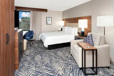 a hotel room with a bed and a chair at Candlewood Suites Columbus North - Worthington by IHG in Columbus