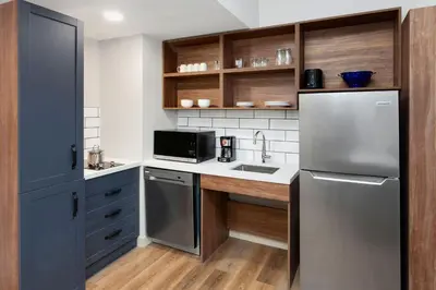 a kitchen with a stainless steel refrigerator and wooden cabinets at Candlewood Suites Columbus North - Worthington by IHG in Columbus