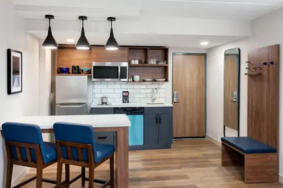 a kitchen with a table and two blue chairs at Candlewood Suites Columbus North - Worthington by IHG in Columbus