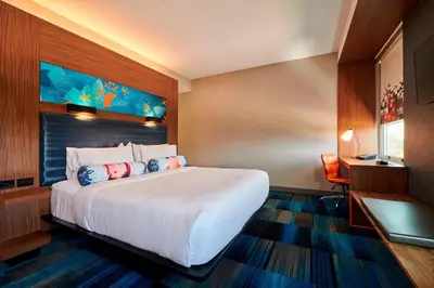 a hotel room with a large bed and a desk at Aloft Cleveland Airport in North Olmsted