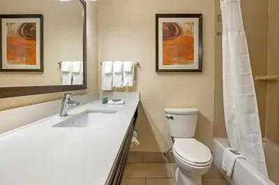 a bathroom with a toilet and a sink and a mirror at Best Western Hilliard Inn & Suites in Hilliard
