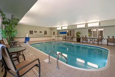 a pool in a hotel room with chairs and tables at Best Western Hilliard Inn & Suites in Hilliard
