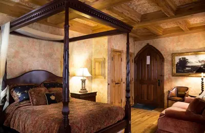 a bedroom with a canopy bed and a chair at Landoll's Mohican Castle in Loudonville