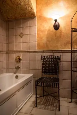 a bathroom with a chair next to a bath tub at Landoll's Mohican Castle in Loudonville