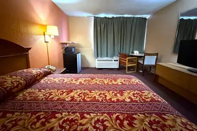 a hotel room with a large bed and a desk at Red Carpet Inn & Suites Lima -Listing Partner in Lima