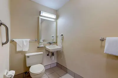 a bathroom with a toilet and a sink and a mirror at Quality Inn Columbus-East in Columbus