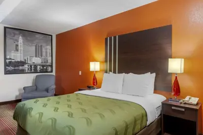 a hotel room with a bed and a chair at Quality Inn Columbus-East in Columbus
