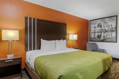 a hotel room with a large bed and a chair at Quality Inn Columbus-East in Columbus