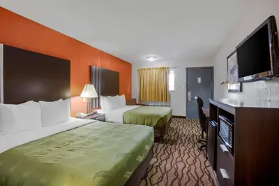 a hotel room with two beds and a flat screen tv at Quality Inn Columbus-East in Columbus