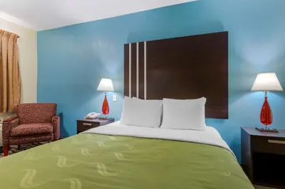 a hotel room with a bed and a chair at Quality Inn Columbus-East in Columbus